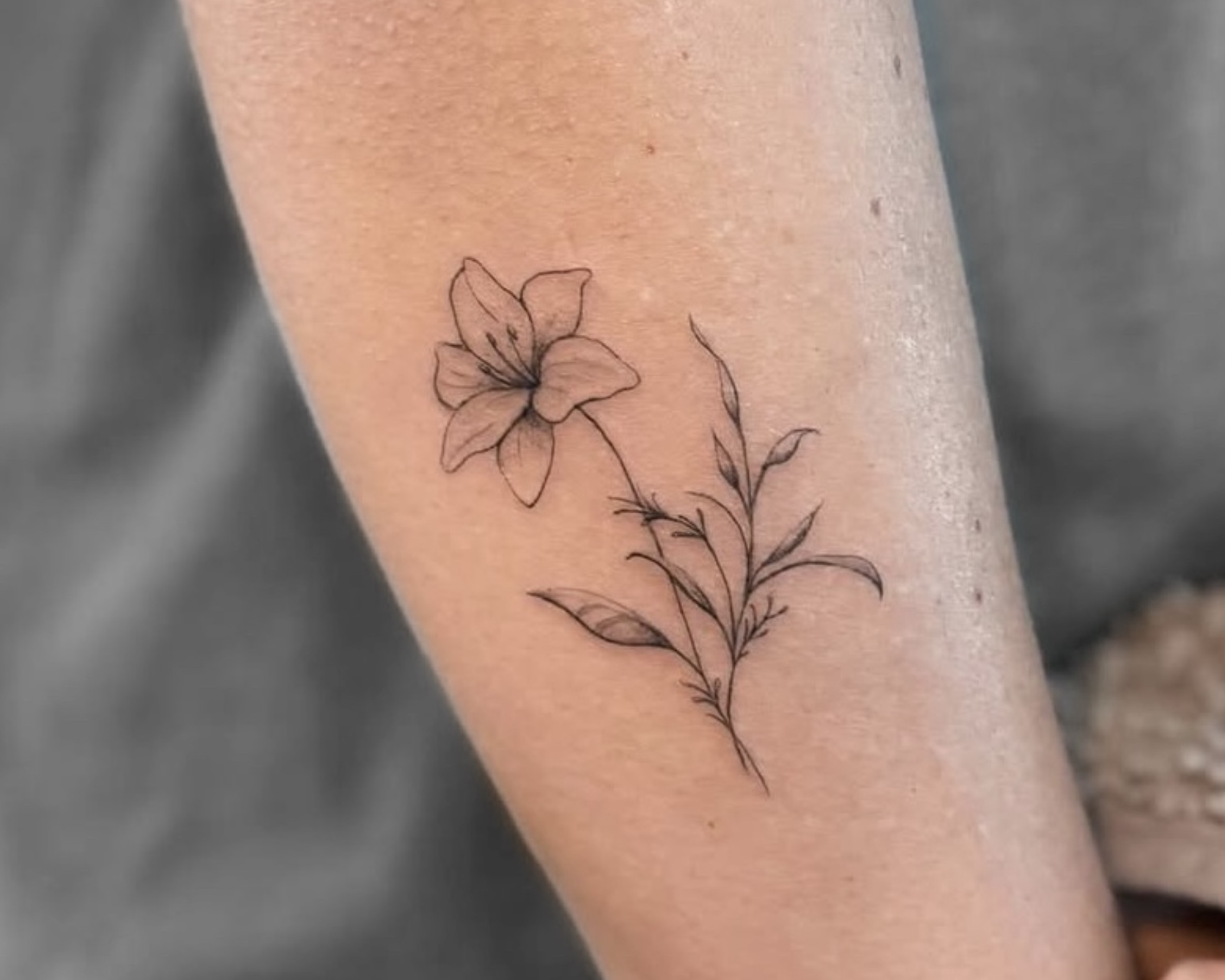 Kleines botanisches Fine Line Blumen-Tattoo am Unterarm in Berlin-Charlottenburg