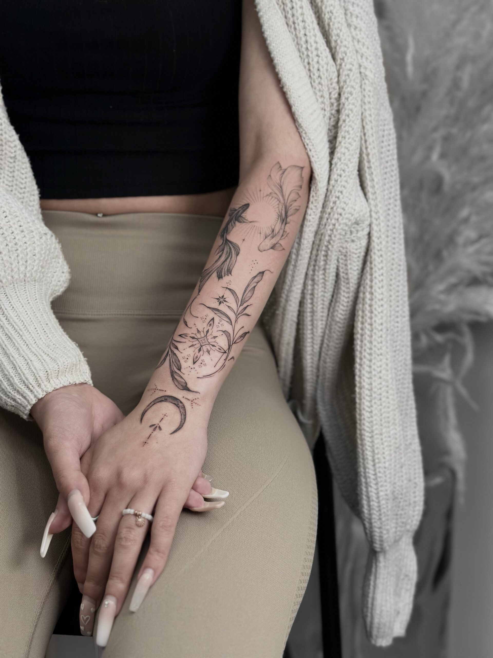 Botanisches fineline Tattoo mit Blumen und Zweigen am Unterarm in Berlin-Charlottenburg