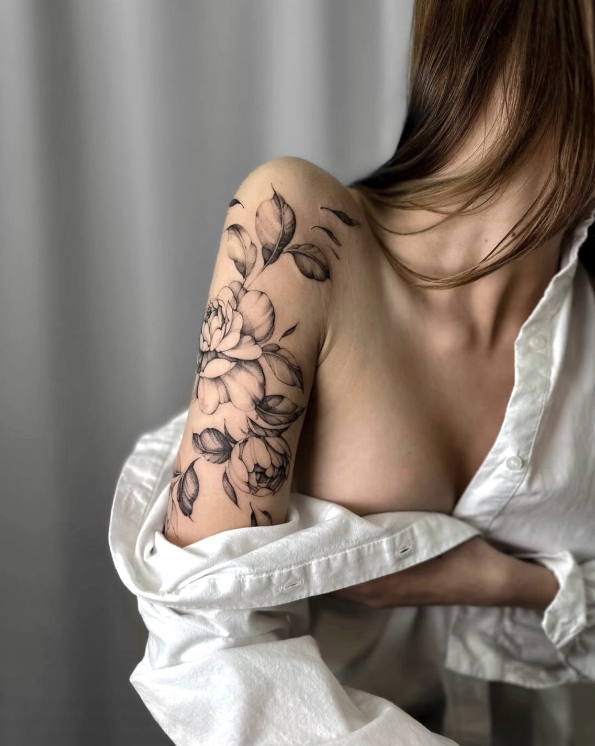 Fine Line Rosen-Tattoo mit Blättern am Unterarm in Berlin-Charlottenburg
