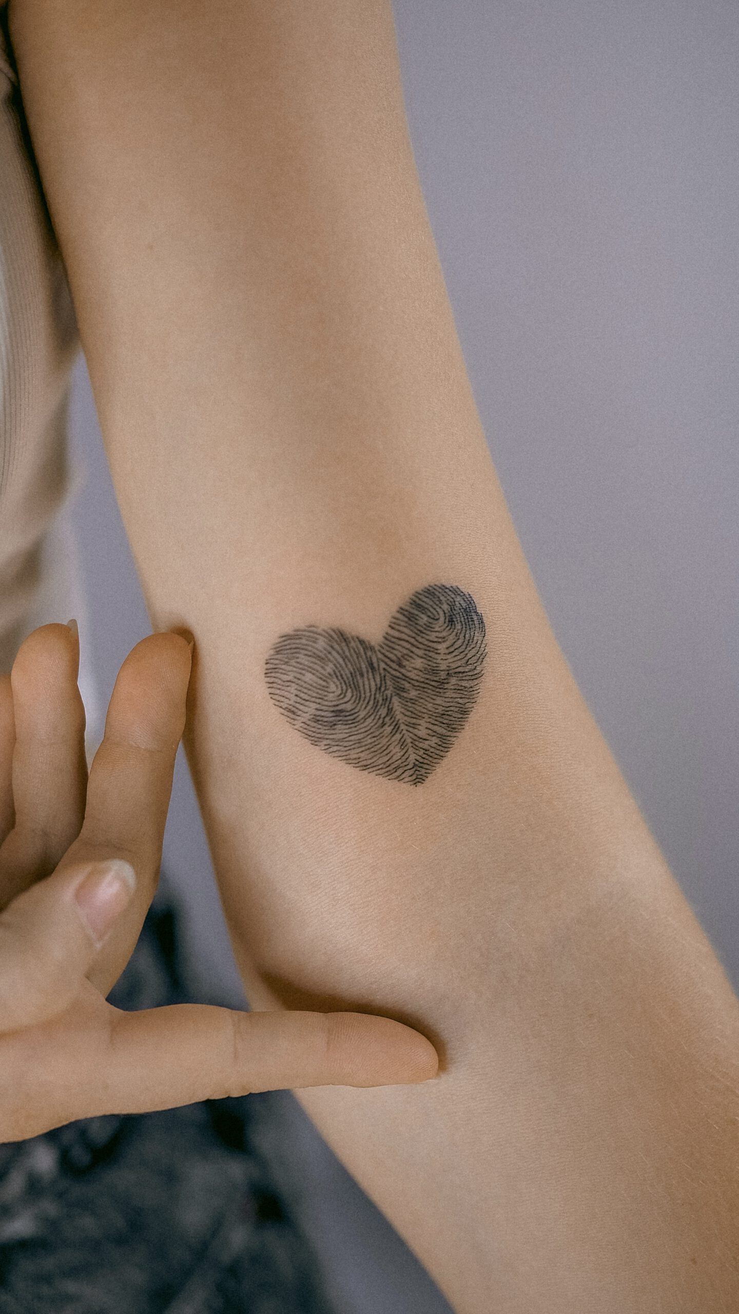 Fineline Fingerabdruck-Herz-Tattoo am Arm in Berlin