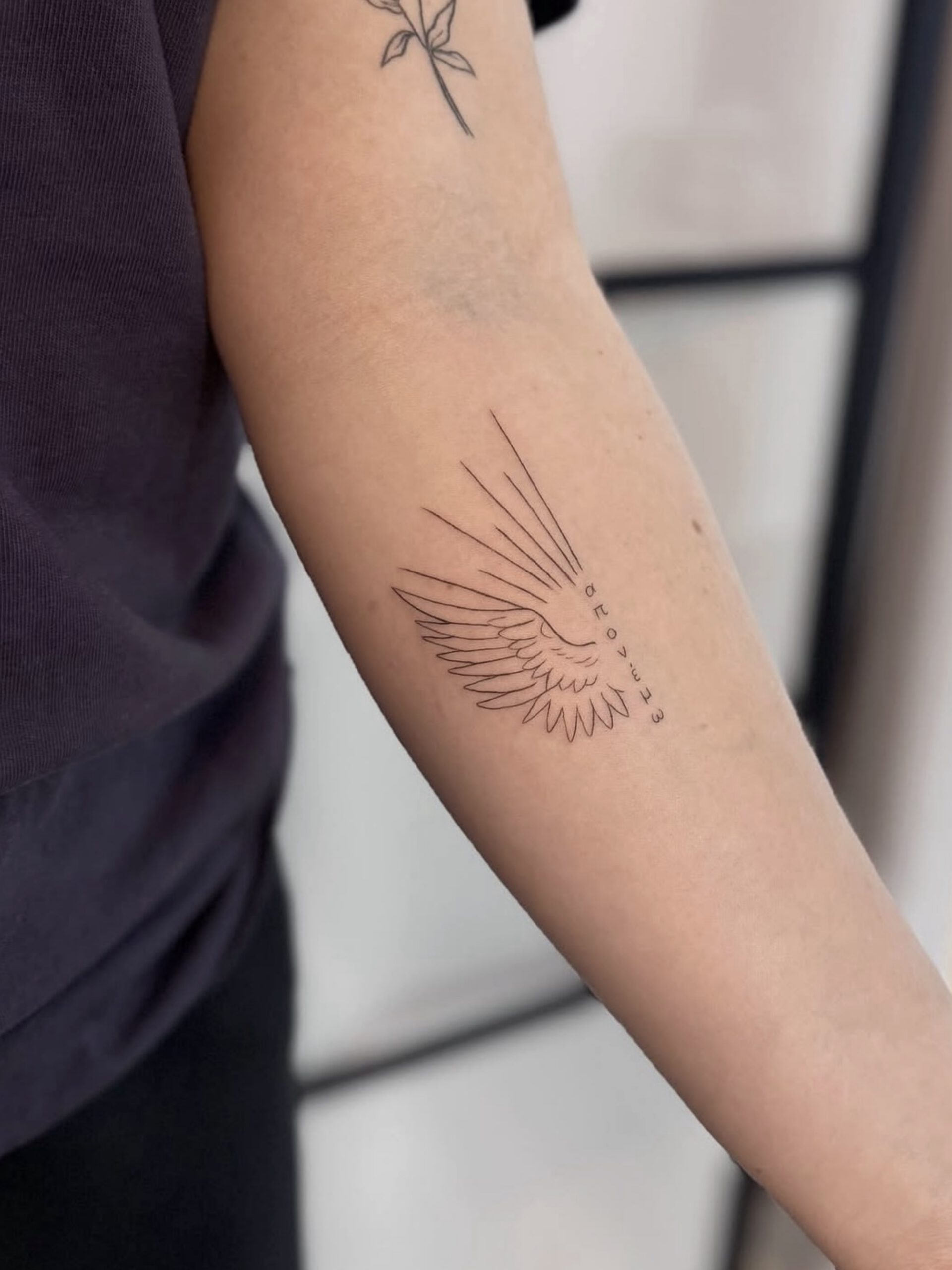 Fineline Flügel-Tattoo mit Federstruktur am Unterarm in Berlin-Schöneberg