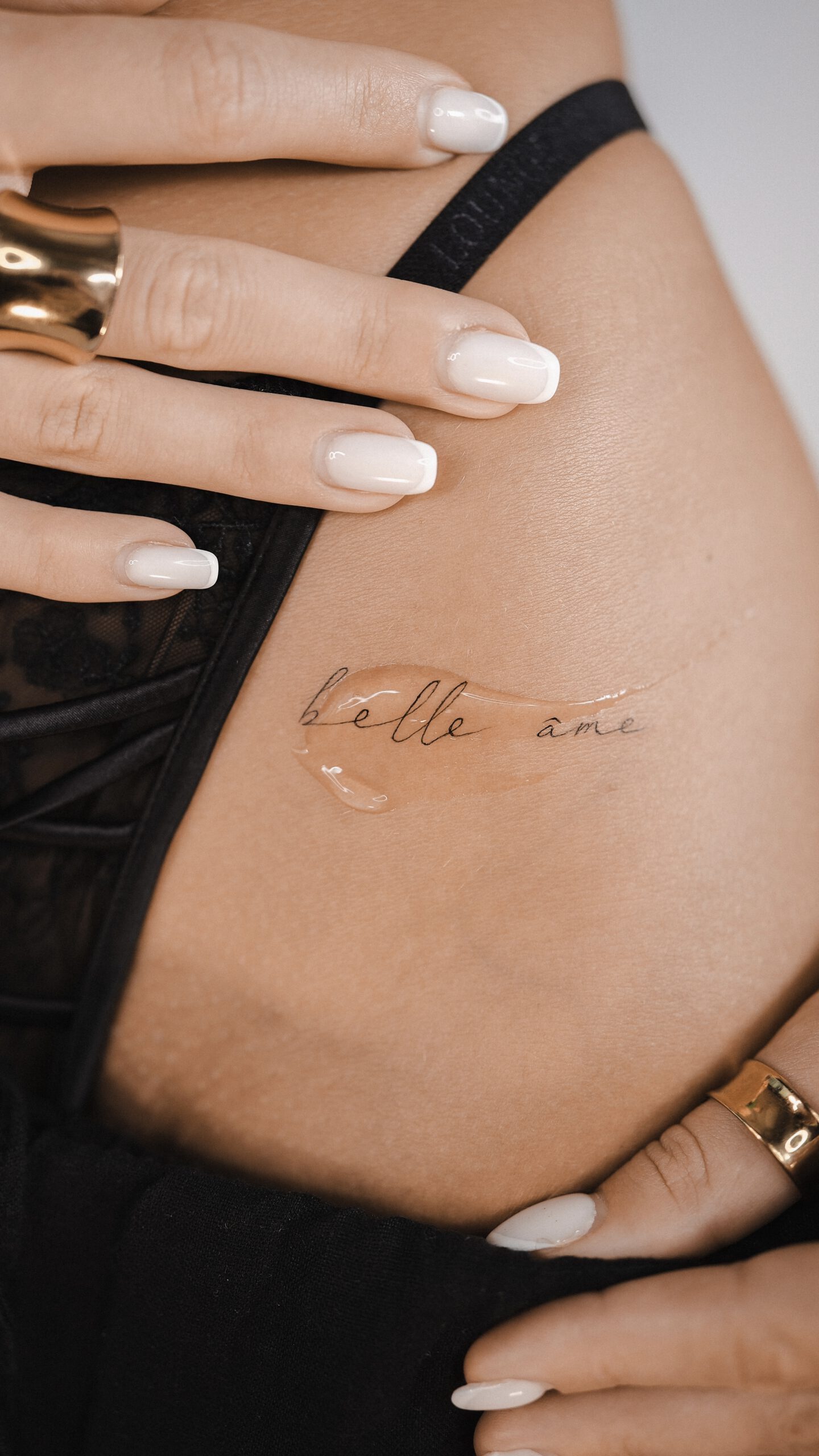 Fineline Schriftzug-Tattoo "belle âme" an der Hüfte in Berlin