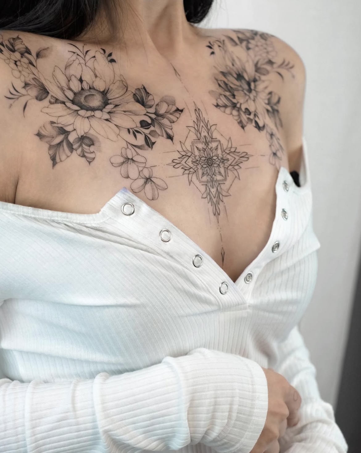 Großes florales Fineline Blumen-Tattoo an Brust und Dekolleté in Berlin