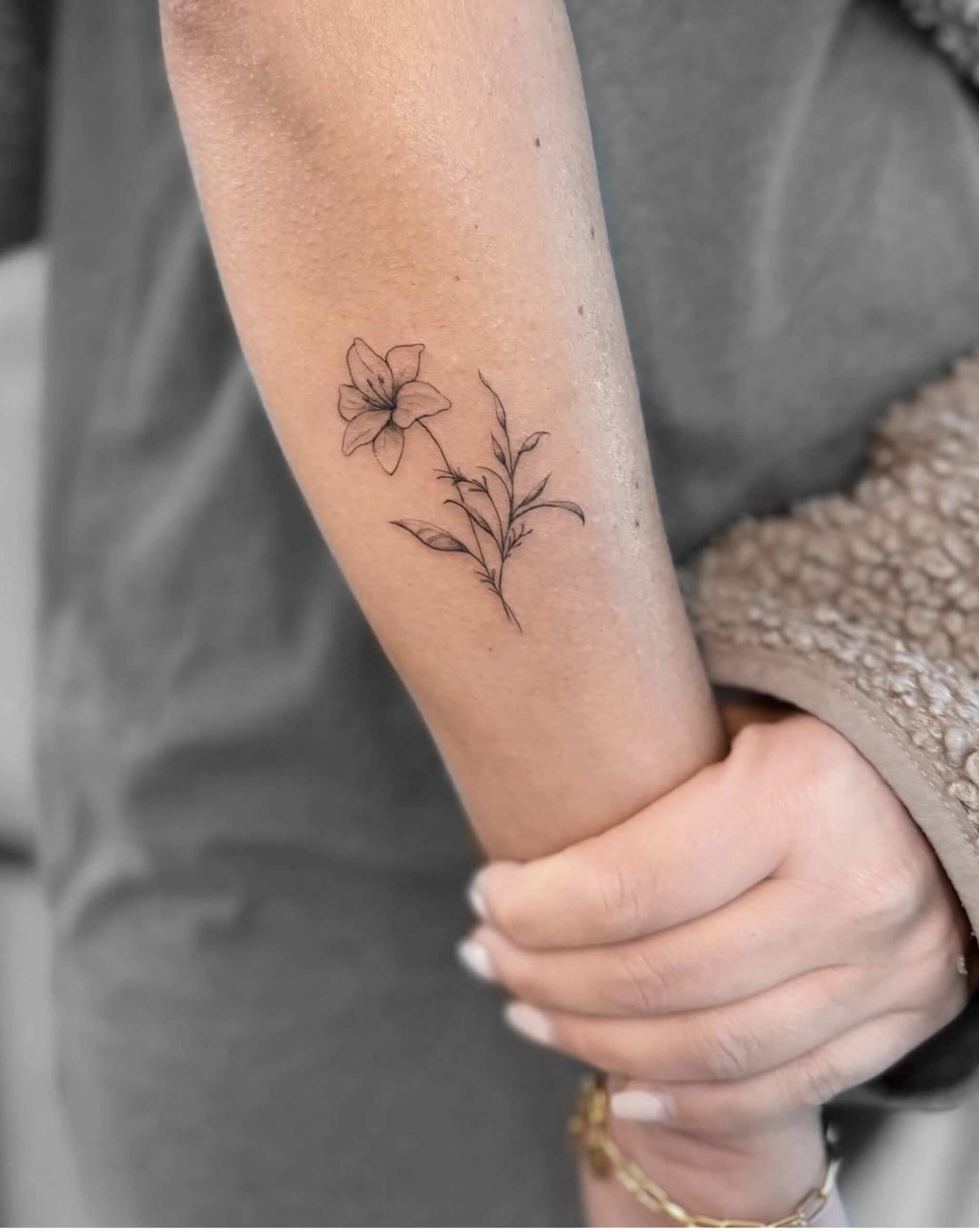 Kleines botanisches Fine Line Blumen-Tattoo am Unterarm in Berlin-Charlottenburg