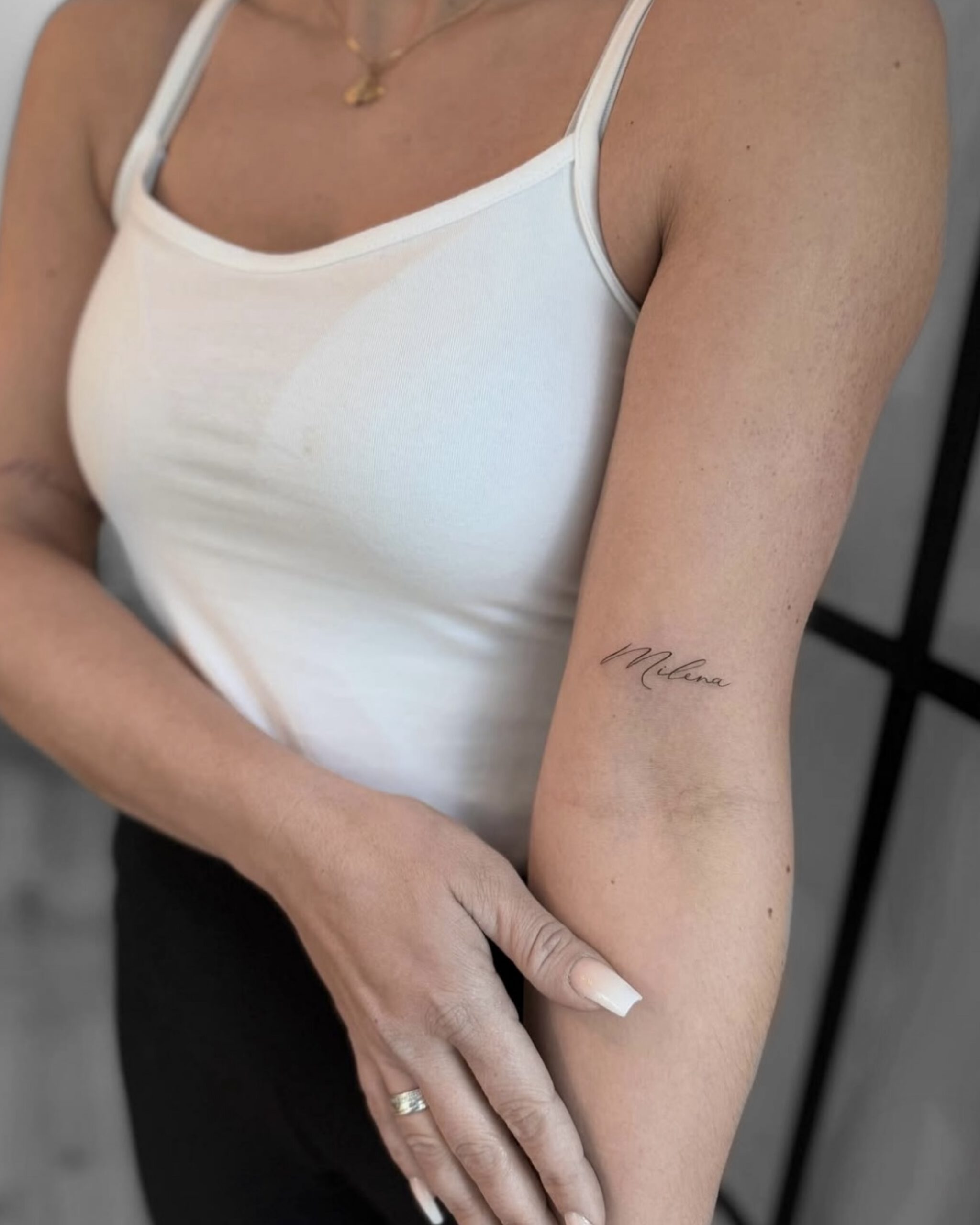 Kleines Fineline Schriftzug-Tattoo an der Innenseite des Oberarms in Berlin