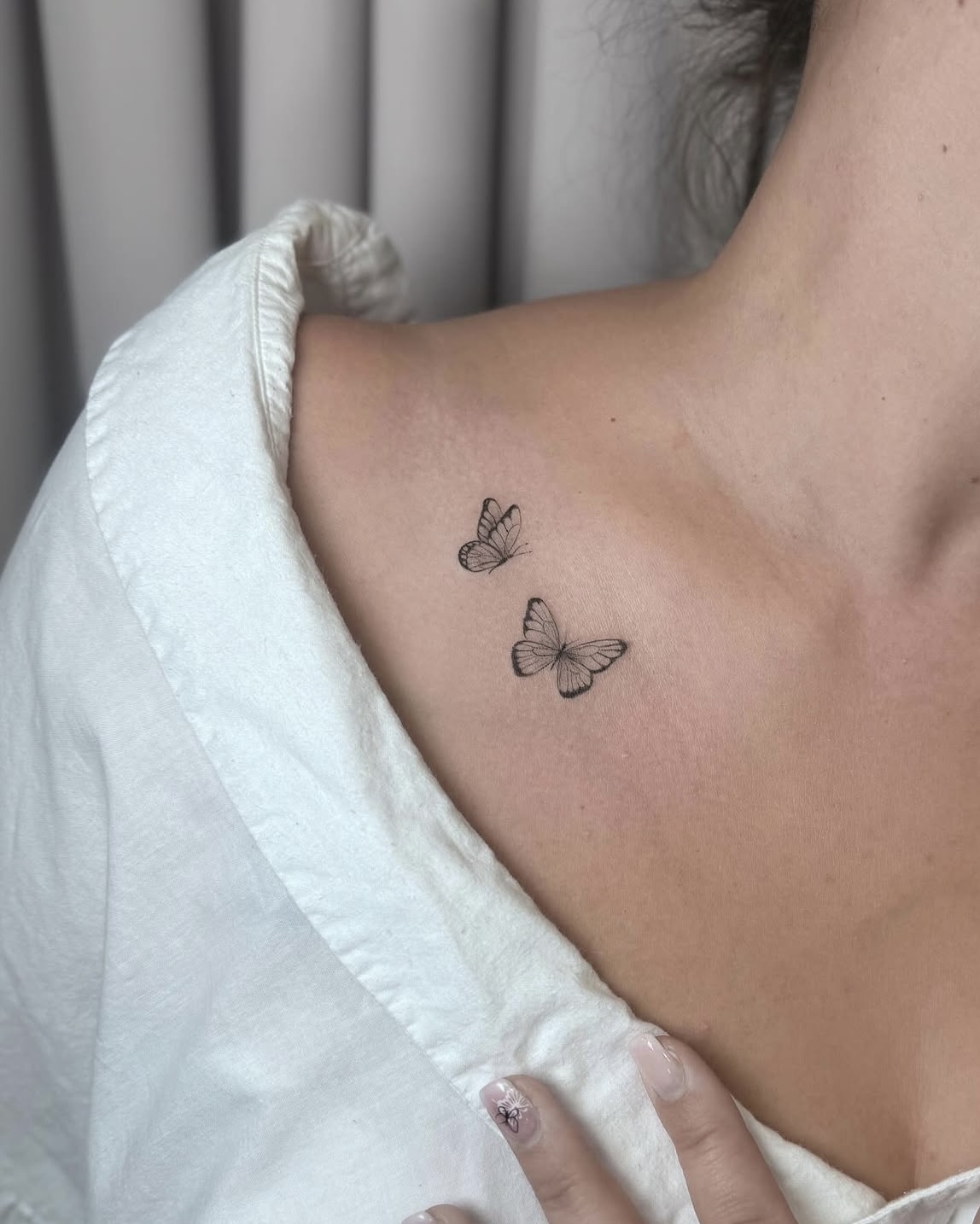 Zwei kleine Fine Line Schmetterling-Tattoos am Schlüsselbein in Berlin