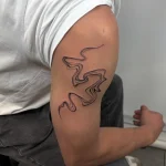 Elegantes, fließendes Fine Line Tattoo mit abstrakten Wellenlinien auf dem Oberarm, gestochen im Black Smoke Tattoo in Berlin.