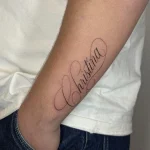 Zartes Custom Lettering Tattoo mit dem Namen Christina in feiner Schreibschrift am Unterarm.