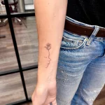 Filigranes Fine Line Tattoo eines Kinderprofils mit blühender Blume am Unterarm, gestochen im BS Tattoo Studio Berlin.