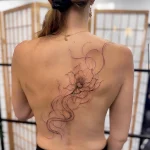 Filigranes Fineline Blumentattoo auf dem Rücken mit eleganten geschwungenen Linien und feinen Details – individuelles Tattoo-Design in Berlin.