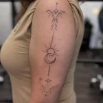 Filigranes Fineline Sonne und Mond Tattoo am Oberarm mit Sternen, feinen Ornamenten und geometrischen Details – elegantes kosmisches Tattoo-Design in Berlin-Charlottenburg.