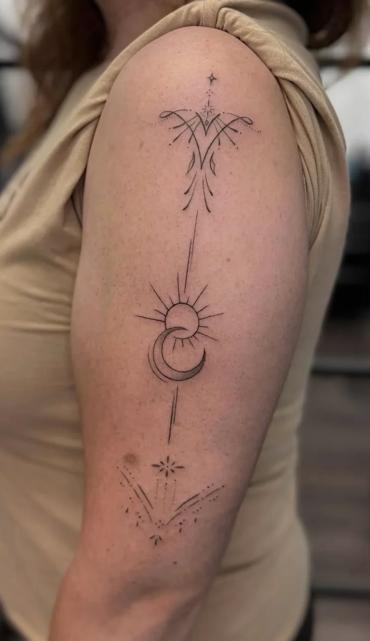 Filigranes Fineline Sonne und Mond Tattoo am Oberarm mit Sternen, feinen Ornamenten und geometrischen Details – elegantes kosmisches Tattoo-Design in Berlin-Charlottenburg.