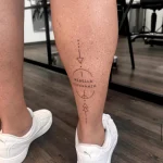 Vertikales geometrisches Tattoo mit dem Schriftzug Rebella Esperanza und minimalistischen Symbolen an der Wade.