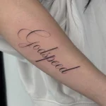 Elegantes Fine Line Schriftzug Tattoo mit dem Wort Godspeed in geschwungener Calligraphy-Schrift am Unterarm.