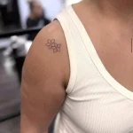 Zartes kleines Fineline Blumentattoo an der Schulter mit mehreren filigranen Blüten – minimalistisches und dezentes Tattoo-Design in Berlin.