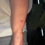 Zartes, minimalistisches Fine Line Lettering Tattoo des Buchstabens 'C' am Handgelenk, kreiert in unserem Schöneberg Tattoo Studio.