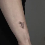Winziges, hochpräzises Microrealismus Tattoo einer Biene mit feinsten Schattierungen am Unterarm.
