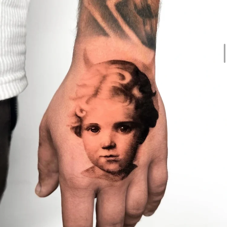 Feinstes Microrealismus Tattoo eines lachenden Babys auf dem Unterarm mit weichen Schattierungen, umgesetzt bei BS Tattoo.