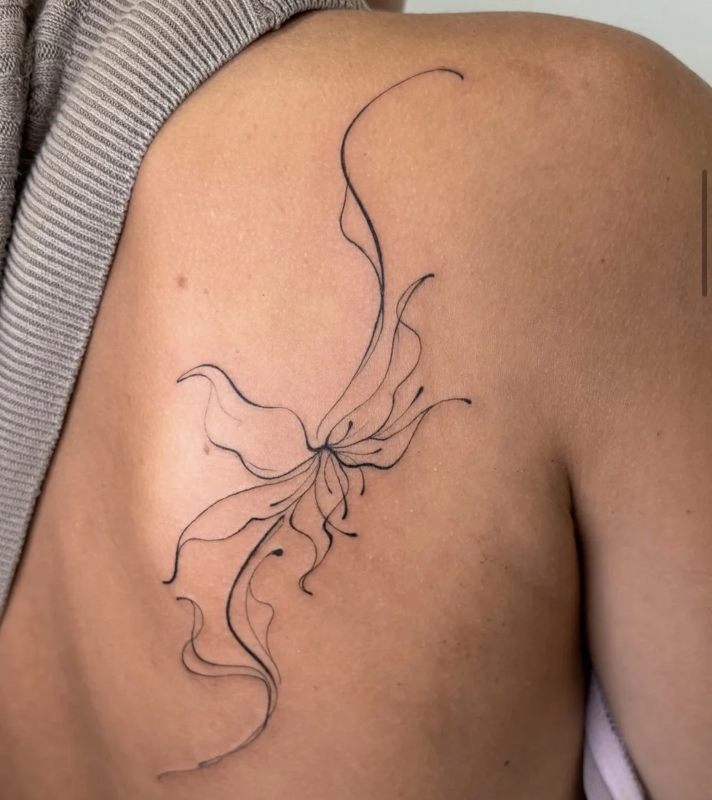 Elegantes, geschwungenes Fine Line Tattoo einer abstrakten Blüte auf dem Schulterblatt.