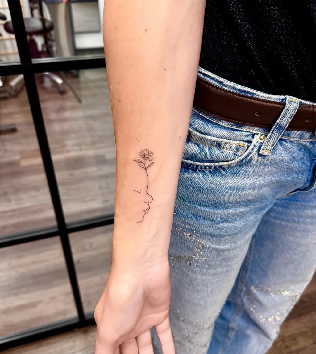 Filigranes Fine Line Tattoo eines Kinderprofils mit blühender Blume am Unterarm, gestochen im BS Tattoo Studio Berlin.
