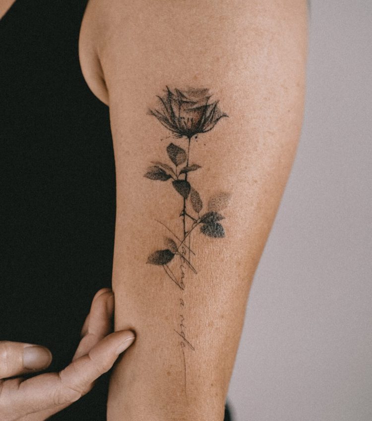 Fineline Rose-Tattoo mit Schriftzug am Oberarm in Berlin-Charlottenburg